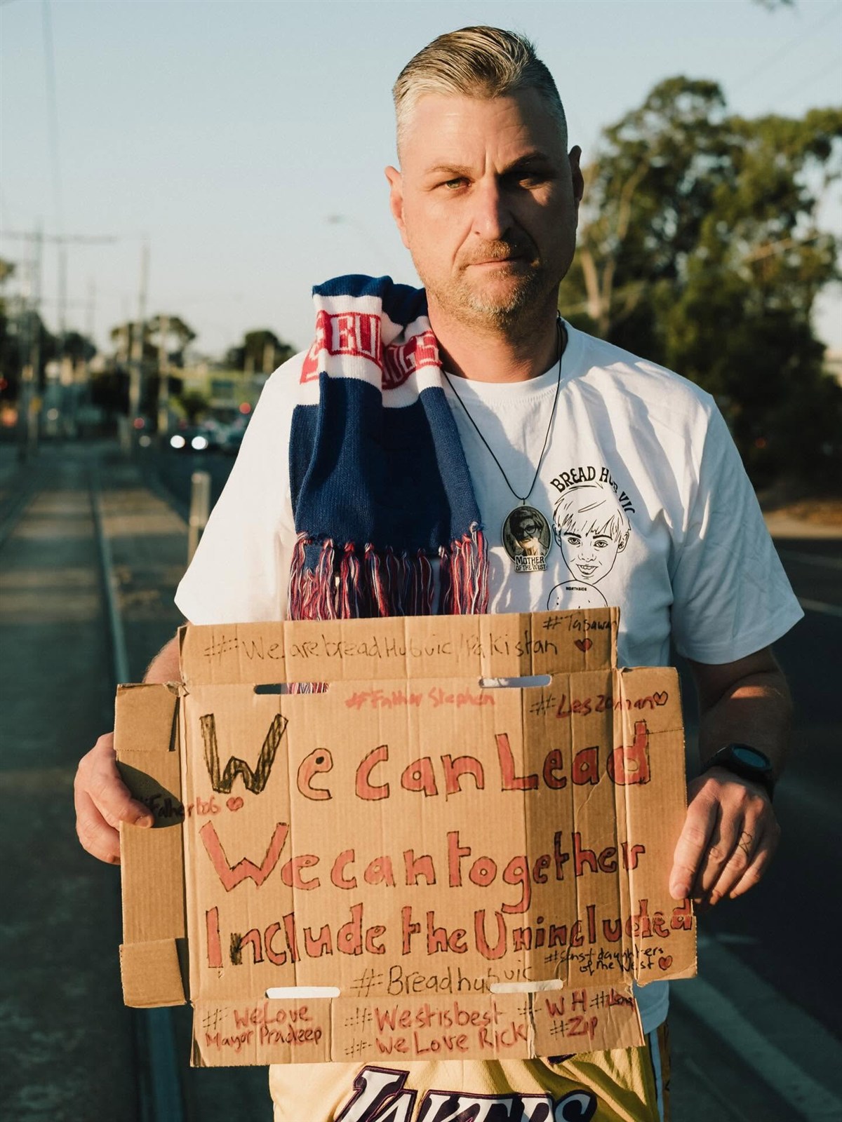 Brendan Murphy holding a sign that reads ‘We can lead. We can together. Include the Unincluded.’