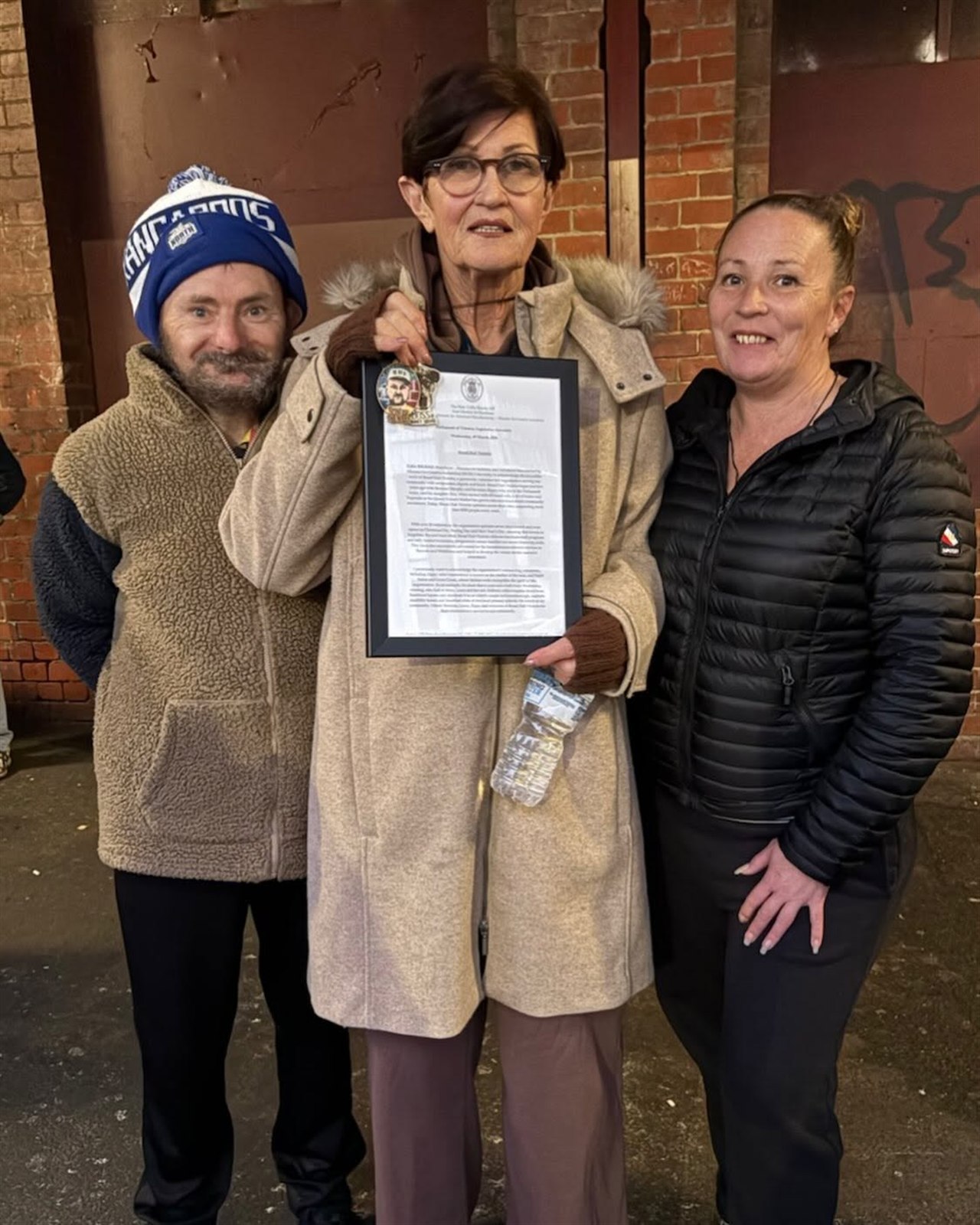 Community members holding a framed recognition certificate